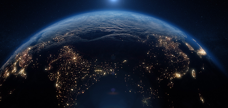 Earth viewed from space at night, showcasing illuminated cities and natural features against a dark backdrop.