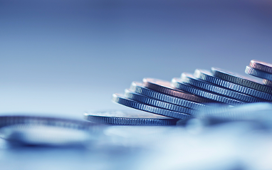 A close-up view of a pile of assorted coins stacked on a wooden table.