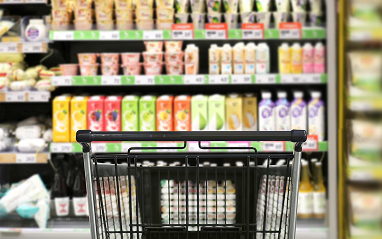 A shopping cart is positioned in front of a grocery store entrance, ready for customers to use for their shopping.